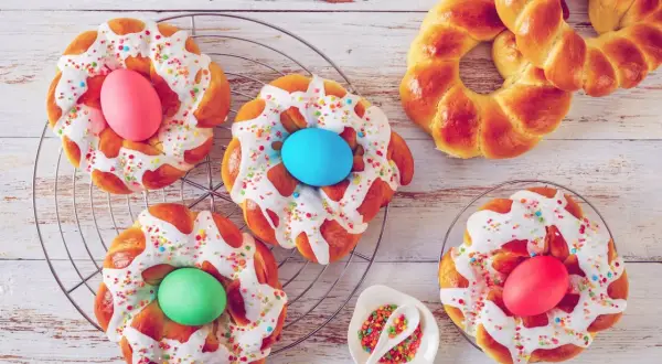 Bunte Osternester backen: Hefezöpfe mit Zuckerguss, Streuseln und gefärbten Eiern.