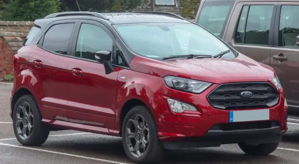 Czerwony Ford EcoSport 2018 z czarnym dachem, zaparkowany na mokrym parkingu.