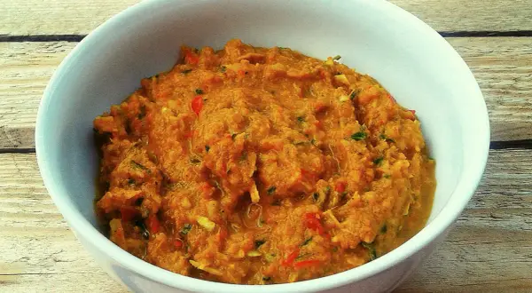 Miska z domową pastą curry o pomarańczowym kolorze, z widocznymi kawałkami warzyw i ziół.