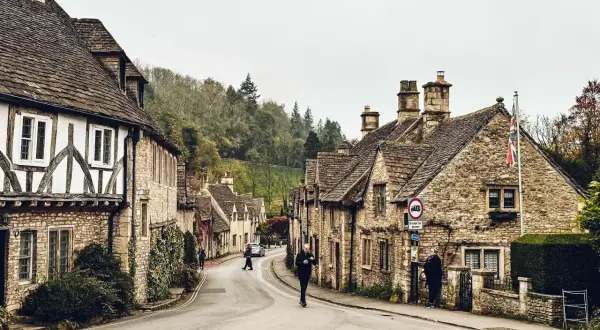 Kamienna uliczka w Cotswolds, z tradycyjnymi domami i drzewami na wzgórzach.