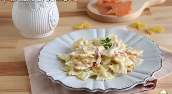 Farfalle al salmone cremose, un piatto invitante con pasta a forma di farfalla e pezzetti di salmone affumicato, guarnito con prezzemolo fresco.