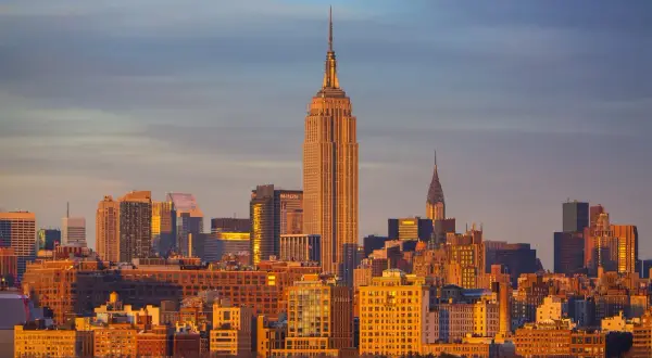 Zachód słońca nad Manhattanem, z Empire State Building i Chrysler Building w tle. Zastanawiasz się, ile się leci do Nowego Jorku?