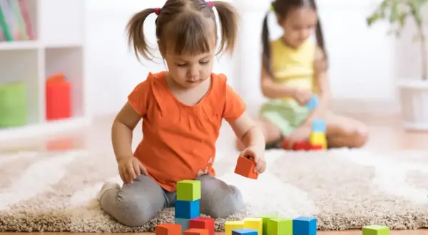 Dwie dziewczynki bawią się klockami. Jedna z nich, z kitkami, układa wieżę. To inwestycja w przyszłość, jak 12 tys na dziecko.