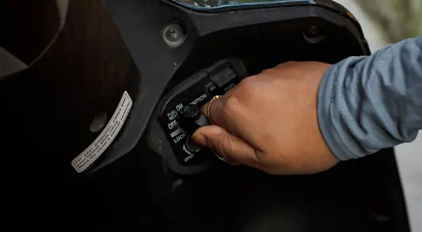 Mano girando la llave de encendido por magneto en una motocicleta.