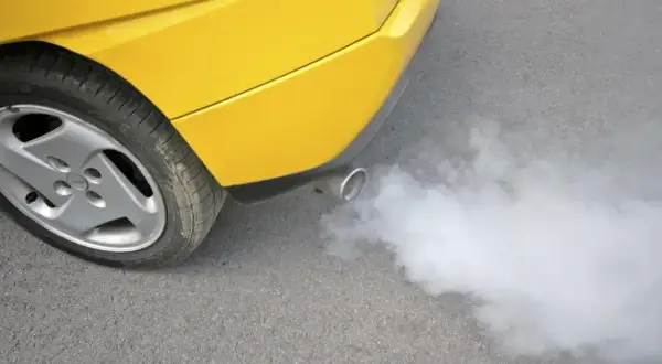 Żółte auto z wydechu pluje białą parą, jakby miało gorączkę.