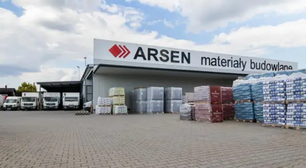 Budynek ARSEN materiały budowlane. Przed magazynem stoją ciężarówki i palety z materiałami. Sprawdź godziny otwarcia!