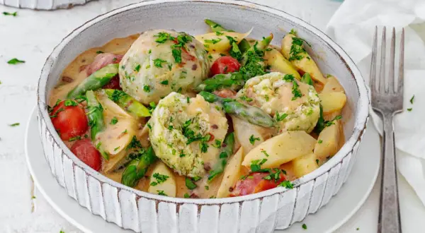 Spargel mal anders: cremiger Eintopf mit Klößen, Kartoffeln, Kirschtomaten und grünen Bohnen, garniert mit Petersilie.