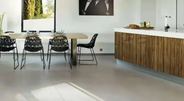 Un salon moderne avec une table en bois, des chaises noires design et un îlot de cuisine en bois. Le sol en carrelage clair complète l'ensemble.