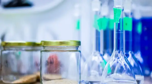 Laboratorium przygotowuje się do analizy. Widać słoiki z próbkami i kolby z płynami, gotowe do wykonania testu na narkotyki z krwi.