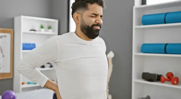 Uomo con mal di schiena, in un centro di fisioterapia, pronto a curare il mal di schiena con esercizi e terapie.