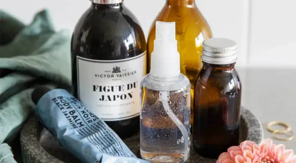 Flera flaskor och en tub med hudvårdsprodukter, inklusive en sprayflaska som kan användas för ett saltvattenspray recept.