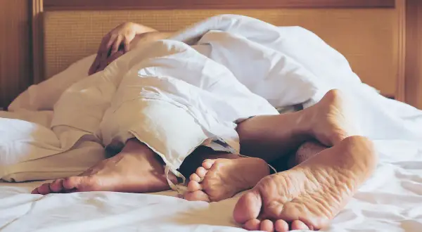Stopy w pościeli, dłonie splatające się pod kołdrą. Chwila intymności, sensualny sex.