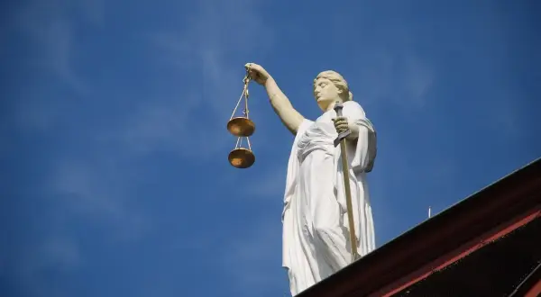 Posąg Temidy z wagą i mieczem na tle błękitnego nieba. Symbol sprawiedliwości, 4cmc.