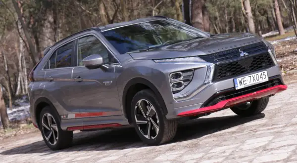 Szary Mitsubishi Eclipse Cross EV na leśnej drodze. Wiele pozytywnych mitsubishi eclipse cross opinie potwierdza jego wszechstronność.