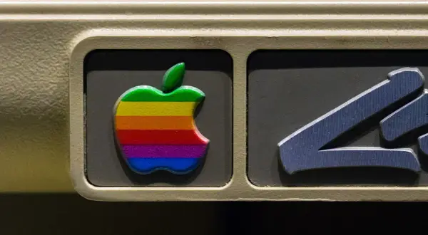 The iconic rainbow Apple logo, a testament to the original apple logo designer's vision, adorns an old computer.
