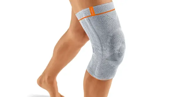 Ein Bein mit einer grauen Kniebandage. Die Bandage könnte bei falscher Anwendung oder zu engem Sitz Schmerzen verursachen.