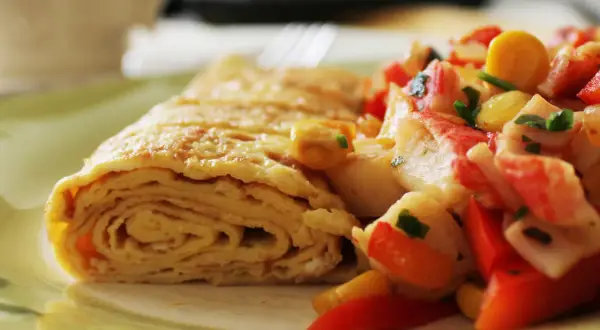 Zrolowany omlet po japońsku z kolorową sałatką z warzyw i surimi.