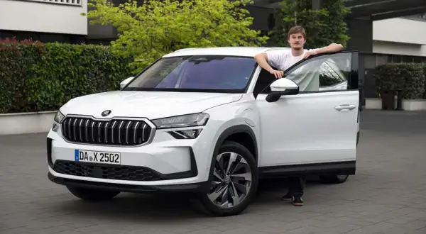 En ung man lutar sig mot en vit Skoda Kodiaq med öppen dörr. En spännande skoda kodiaq test.