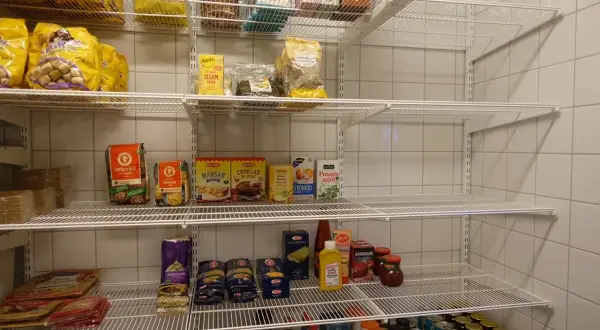 Hylla med basvaror att ha hemma: mjöl, pasta, krossade tomater, senap, sesamfrön och mer.