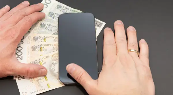 Dłonie przy smartfonie i polskich banknotach. Czy można cofnąć blik?