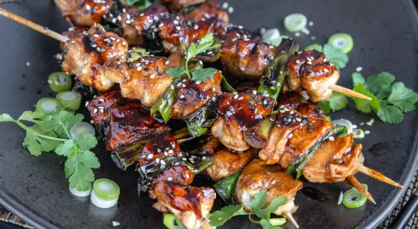 Leckeres Yakitori: saftige Hähnchenspieße mit Teriyaki-Glasur, garniert mit Sesam und Frühlingszwiebeln.