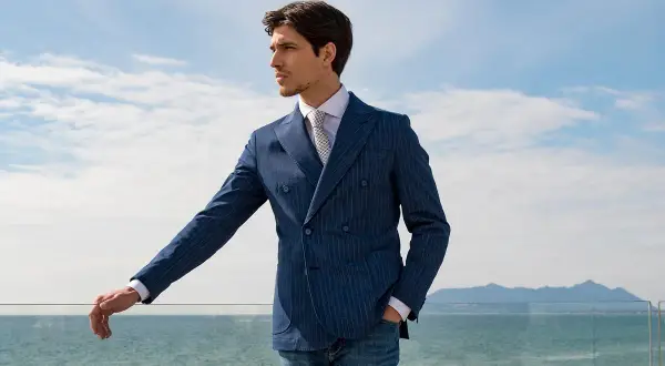 Uomo elegante con abito doppiopetto blu a righe, perfetto come invitato a una cerimonia estiva.