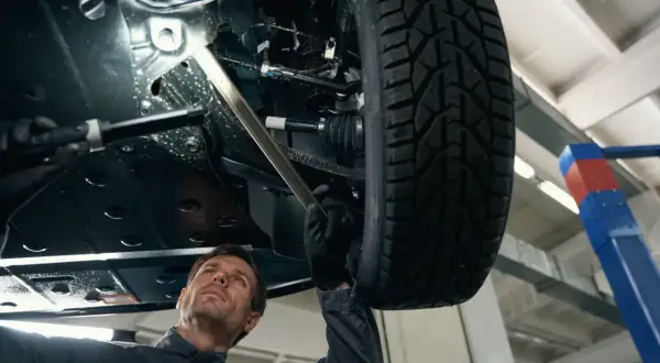Mechanik sprawdza podwozie auta, szukając przyczyny stukania w kole podczas jazdy.