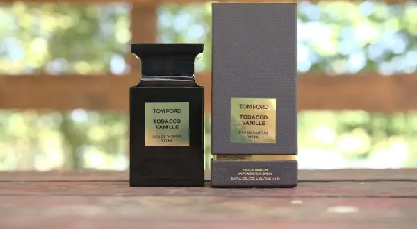 Elegancka butelka i pudełko perfum Tom Ford Tobacco Vanille na drewnianym tle.