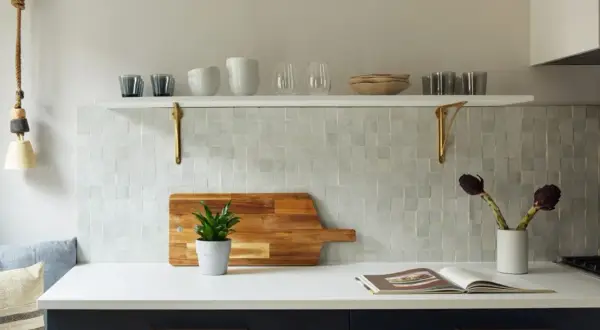 A kitchen backsplash features zellige tile, a Moroccan mosaic of hand-cut, glazed tiles. A wooden cutting board with a plant sits on the counter.