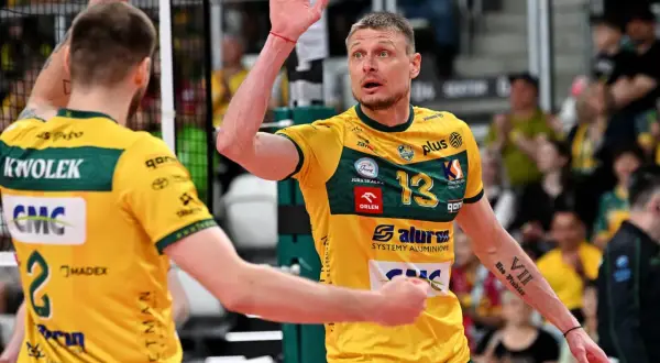 Jurij Gładyr, siatkarz w żółtej koszulce z numerem 13, unosi dłoń z białymi plastrami.