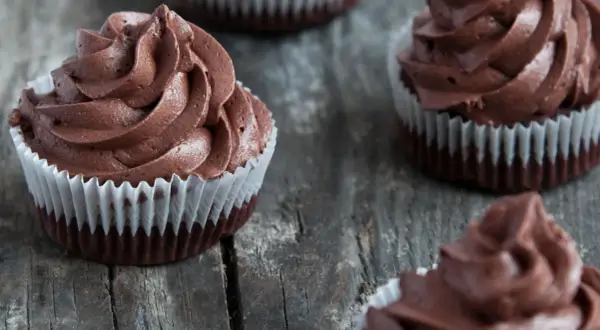 Kilka pysznych muffinek z kremem czekoladowym, ułożonych na drewnianym blacie.