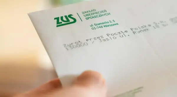Dłoń trzyma kopertę ZUS. Może to zwrot środków, np. 500 plus dla niepełnosprawnych.