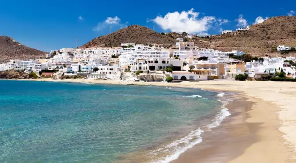 Un pueblo blanco se asoma a una playa dorada y aguas turquesas. Un lugar idílico que ver en Cabo de Gata.