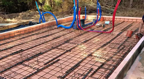 Przygotowania do wylania płyty fundamentowej: zbrojenie i rury instalacyjne.