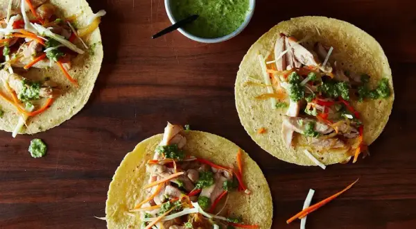 Tre färdiga tacos med kyckling, grönsaker och grön sås. Ett enkelt tacos recept för en god middag.