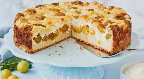 Saftiger Mirabellenkuchen mit Quark und Streuseln auf einem blauen Tortenständer.