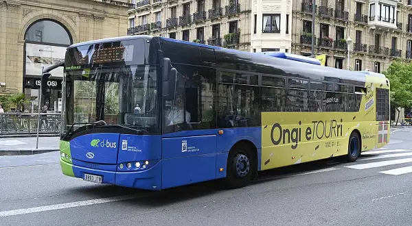 Autobús azul y amarillo de Dbus en Ondarroa, San Sebastián, con el lema "Ongi etorri".