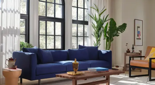 Granatowy salon inspiracje: nowoczesna sofa, drewniana ława, skórzany fotel i duże okna tworzą przytulną przestrzeń.