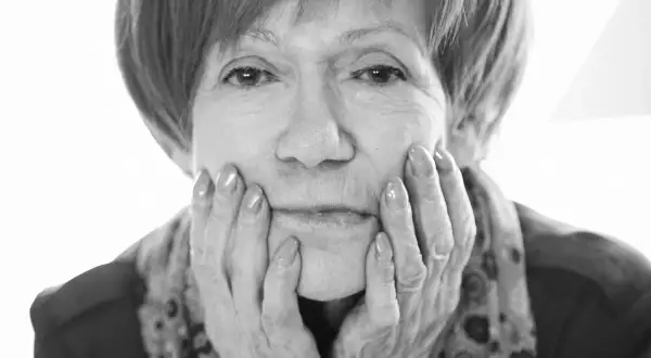 Portret Marii Czubaszek, z dłońmi opartymi o policzki. Jej spojrzenie przywodzi na myśl jej słynne maria czubaszek cytaty.