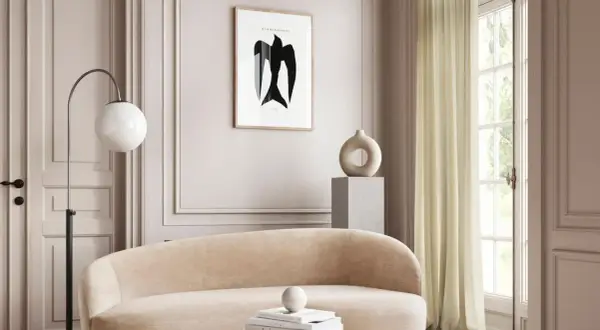 Ein gemütliches Wohnzimmer in greige farbe mit einem geschwungenen Sofa, einem modernen Stehlampen und einem Kunstwerk mit einem Vogel.
