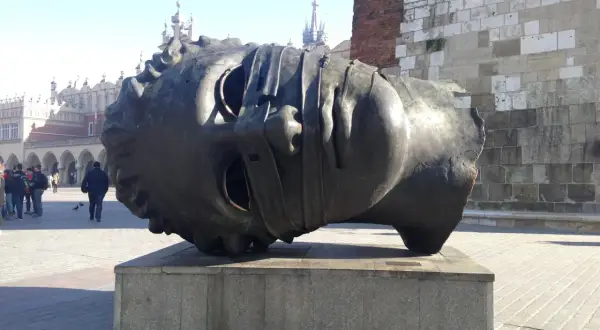 Gigantyczna, metalowa głowa leży na cokole. To intrygująca rzeźba, która przyciąga wzrok przechodniów na rynku.