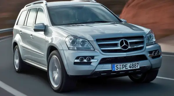 Srebrny Mercedes-Benz GL Class pędzi po drodze, za nim rozmyte krajobrazy.