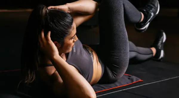 Frau macht Crunches auf einer Matte, ein effektives Bauchtraining für einen starken Rumpf.