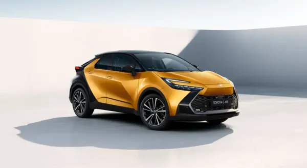Nowy Toyota C-HR w kolorze złotym, z czarnym dachem i felgami. Zbliżenie na przód auta, widoczna nazwa modelu. Poznaj jego wymiary!