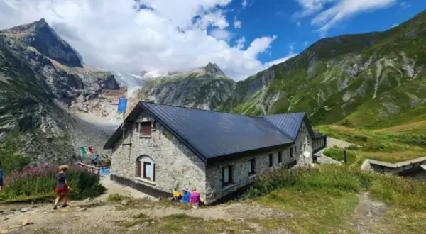 Kamienny schron na GR20 Korsyka, z lodowcem w tle i zielonymi górami.