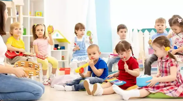 Dzieci na zajęciach muzycznych, grają na instrumentach. Ciekawe, ile zarabia przedszkolanka za taką pracę.