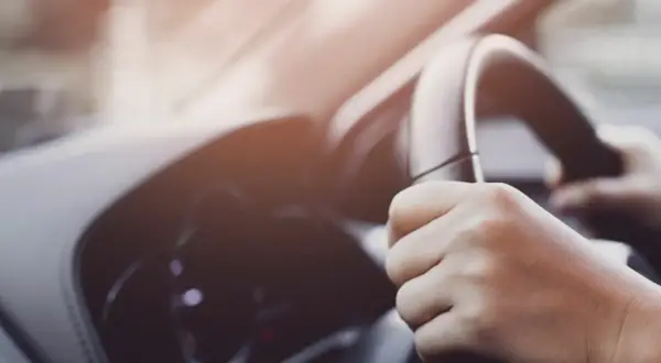 Manos sujetando el volante de un coche, con un ligero ruido al girar el volante.