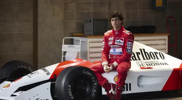 Młody kierowca w czerwonym kombinezonie siedzi na bolidzie F1. Czy to przyszły były brazylijski kierowca formuły 1?