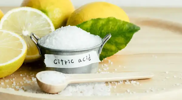 Limoni freschi e un piccolo secchiello con cristalli di acido citrico, che serve per conservare e dare sapore.