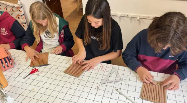 Chicas concentradas en una actividad manual, aprendiendo sobre el IGCSE que es y cómo aplicarlo en proyectos creativos.